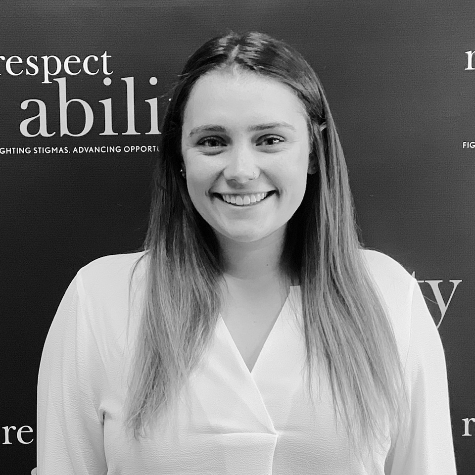 Molly McConville smiling in front of the RespectAbility banner