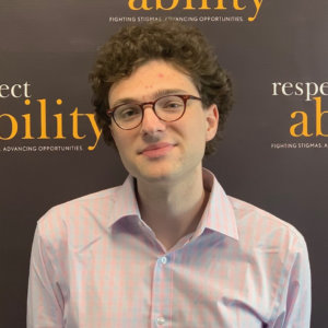 Nemo Charlton smiling in front of the RespectAbility banner