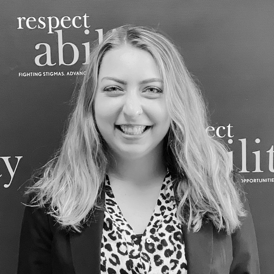 Sarah Meehan smiling in front of the RespectAbility banner