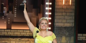 Ali Stroker holds her Tony award in the air on stage at the ceremony