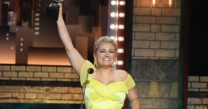 Ali Stroker holds her Tony award in the air on stage at the ceremony