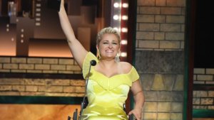 Ali Stroker holds her Tony award in the air on stage at the ceremony