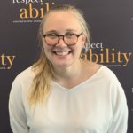 Grace Goldman smiling in front of the RespectAbility banner