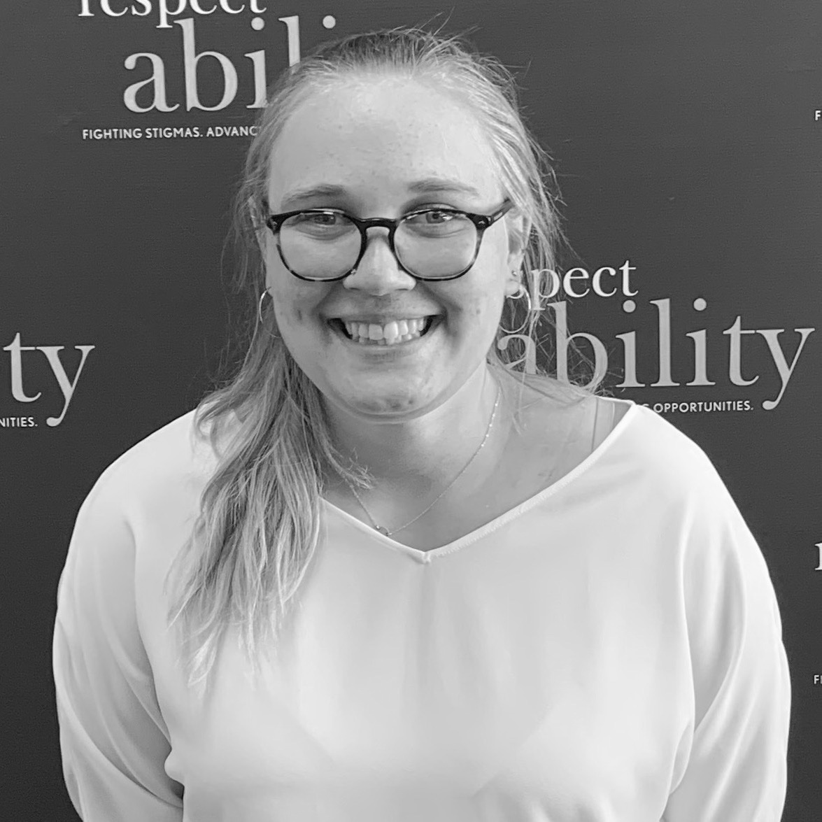 Grace Goldman smiling in front of the RespectAbility banner