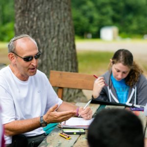 Howard Blas with participants in the Tikvah program sitting outside at a table