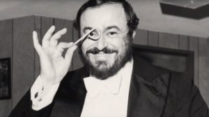 Luciano Pavarotti holding up something in front of his eye, smiling