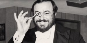 Luciano Pavarotti holding up something in front of his eye, smiling