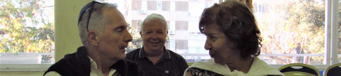 Zvia Admon speaking with a man seated next to her while another man sits behind both of them