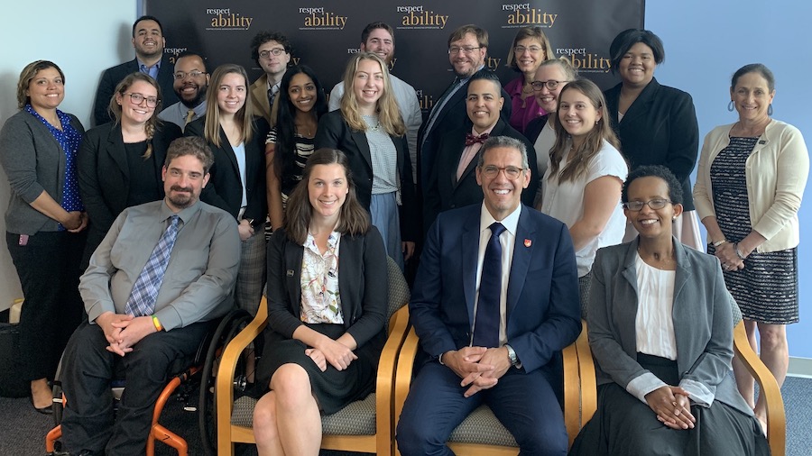 Richard Phillips with RespectAbility Staff and Fellows smiling in front of the RespectAbility banner