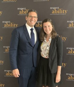 Richard Phillips with Abigail Alvarez smiling in front of the RespectAbility banner