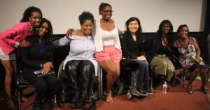 Six women of color with disabilities at the Women of Color Disability Summit on stage together, smiling