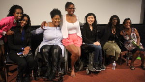 Six women of color with disabilities at the Women of Color Disability Summit on stage together, smiling