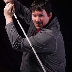 Dan Mouyard holding a white cane like a sword, smiling