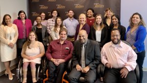 Apoorva Ghandi with RespectAbility staff and Fellows smiling in front of the RespectAbility banner