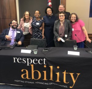 Self Advocacy Panelists at the 2019 RespectAbility Summit smile together behind a table with RespectAbility's logo on it