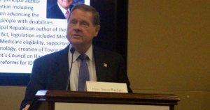 Steve Bartlett speaking in front of a screen with his biography on it behind a podium