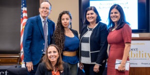 Top row L-R: Jonathan Murray, Nasreen Alkhateeb, Lauren Appelbaum and Teresa Hammond. Candace Cable in second row. All are smiling together in front of RespectAbility's podium, screen, and an American flag