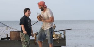Zak (Zack Gottsagen), left, and Tyler (Shia LaBeouf), right, near a raft they built in “The Peanut Butter Falcon”