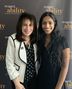Vivian Bass and Shivani Gandhi smiling together in front of the RespectAbility banner