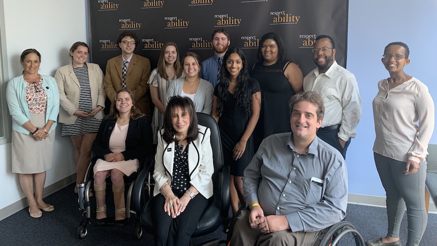 Vivian Bass with RespectAbility Staff and Summer 2019 Fellows smiling in front of the RespectAbility banner