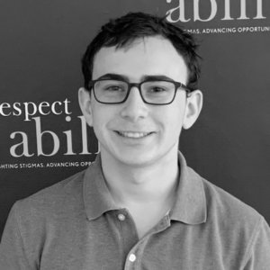 Eitan Jacobsohn smiling in front of the RespectAbility banner