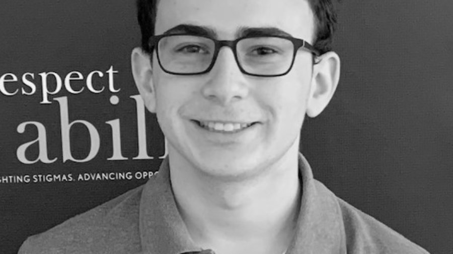 Eitan Jacobsohn smiling in front of the RespectAbility banner