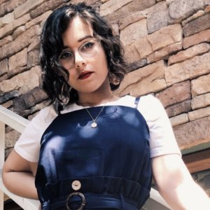 Andrea Lausell leaning against a staircase railing in front of a wall