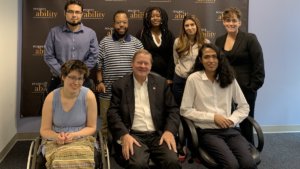 Rep. Steve Bartlett with RespectAbility Fall 2019 Fellows smiling in front of the RespectAbility banner