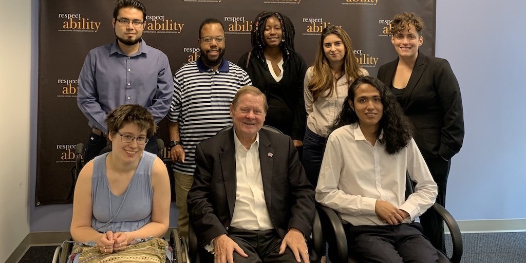 Rep. Steve Bartlett with RespectAbility Fall 2019 Fellows smiling in front of the RespectAbility banner