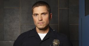 Eric Winter as Tim Bradford wearing a police uniform with badge on The Rookie