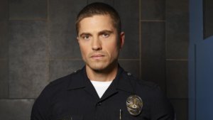 Eric Winter as Tim Bradford wearing a police uniform with badge on The Rookie