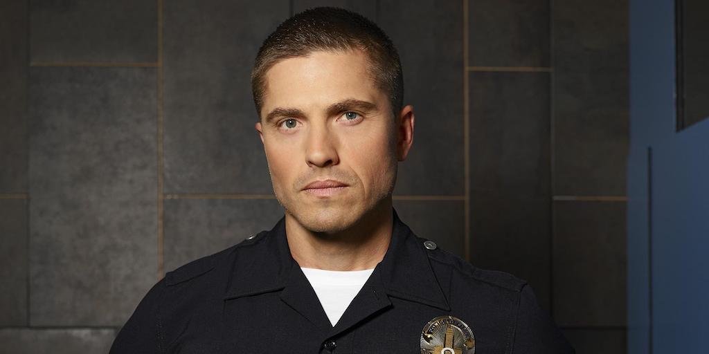 Eric Winter as Tim Bradford wearing a police uniform with badge on The Rookie