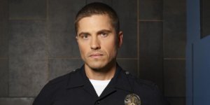 Eric Winter as Tim Bradford wearing a police uniform with badge on The Rookie