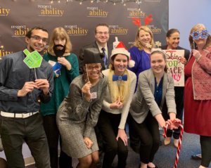 RespectAbility Fall 2018 Fellows with Debbie Fink wearing holiday-related accessories in front of the RespectAbility banner