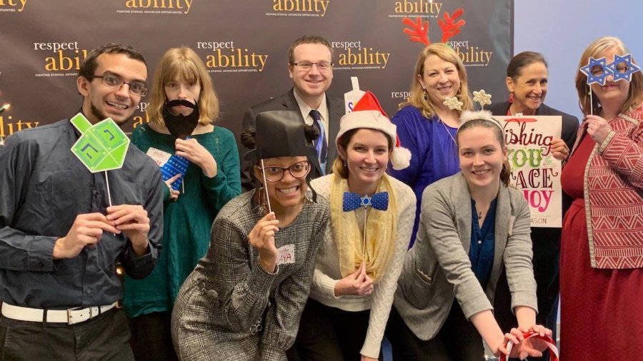 RespectAbility Fall 2018 Fellows with Debbie Fink wearing holiday-related accessories in front of the RespectAbility banner