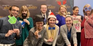 RespectAbility Fall 2018 Fellows with Debbie Fink wearing holiday-related accessories in front of the RespectAbility banner