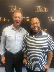 Larry Lipman and Anthony Brown smile together in front of the RespectAbility banner