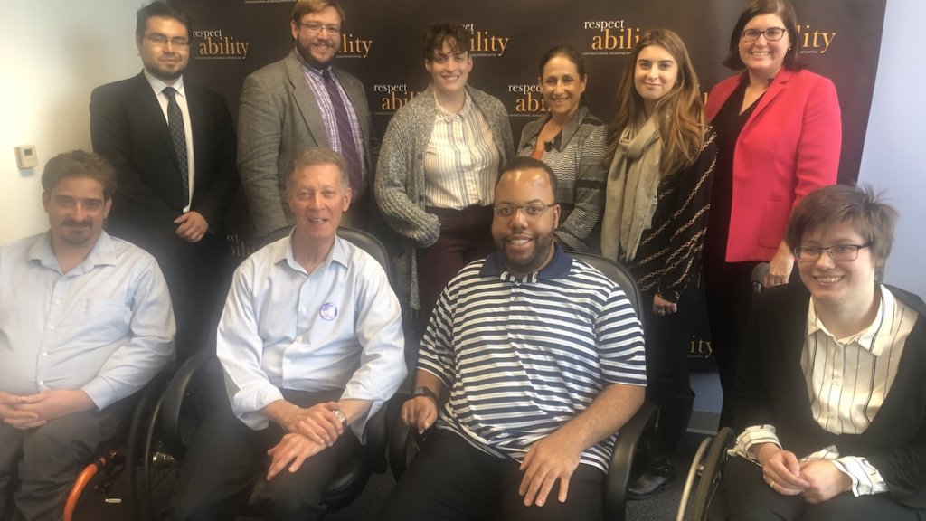 Larry Lipman with RespectAbility staff and Fellows in front of the RespectAbility banner, all smiling