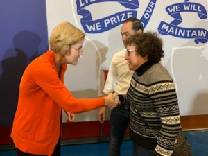 Elizabeth Warren shakes hands with Ila Eckhoff as Julian Castro looks on.