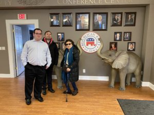 Eric Ascher, James Trout and Ila Eckhoff in front of photos of Republican elected officials, the Iowa Republican Party seal, and two elephant statues