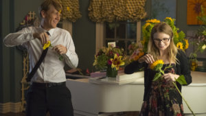 Josht Thomas and Kayla Cromer picking flower petals off of flowers inside a kitchen in a scene from Everything's Gonna Be Okay.