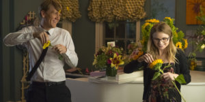 Josht Thomas and Kayla Cromer picking flower petals off of flowers inside a kitchen in a scene from Everything's Gonna Be Okay.