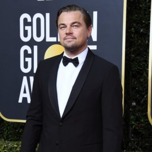 Leonardo DiCaprio smiling on the Golden Globes red carpet in front of a sign for the award show