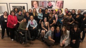 Women with disabilities smile together inside Positive Exposure's art gallery in New York City