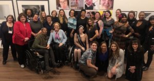 Women with disabilities smile together inside Positive Exposure's art gallery in New York City