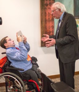Justin Chappell holds an iPad filming Bernie Sanders giving an answer to a question he asked
