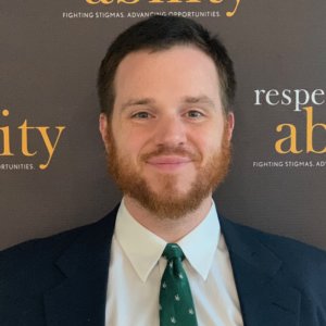 Geoff Hoppe smiling in front of the RespectAbility banner