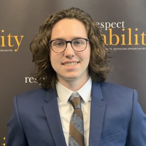 John “Jack” Rukeyser smiling in front of the RespectAbility banner