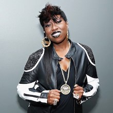 Missy Elliot smiling for the camera, dressed in a black and white outift