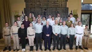 Israeli President Rivlin and Special in Uniform soldiers smile together in front of Israeli flags, standing on steps